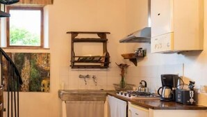 A kitchen with a chandelier, wooden beams, a sink, and a stove. - AGRITURISMO QUARANTALLINA (Buonconvento)