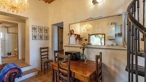 A dining area with a wooden table, chairs, a chandelier, and a mirror above the table. - AGRITURISMO QUARANTALLINA (Buonconvento)