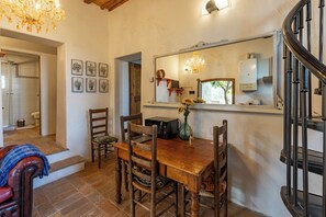 Un comedor con una mesa de madera, sillas, una lámpara de araña y un espejo sobre la mesa.