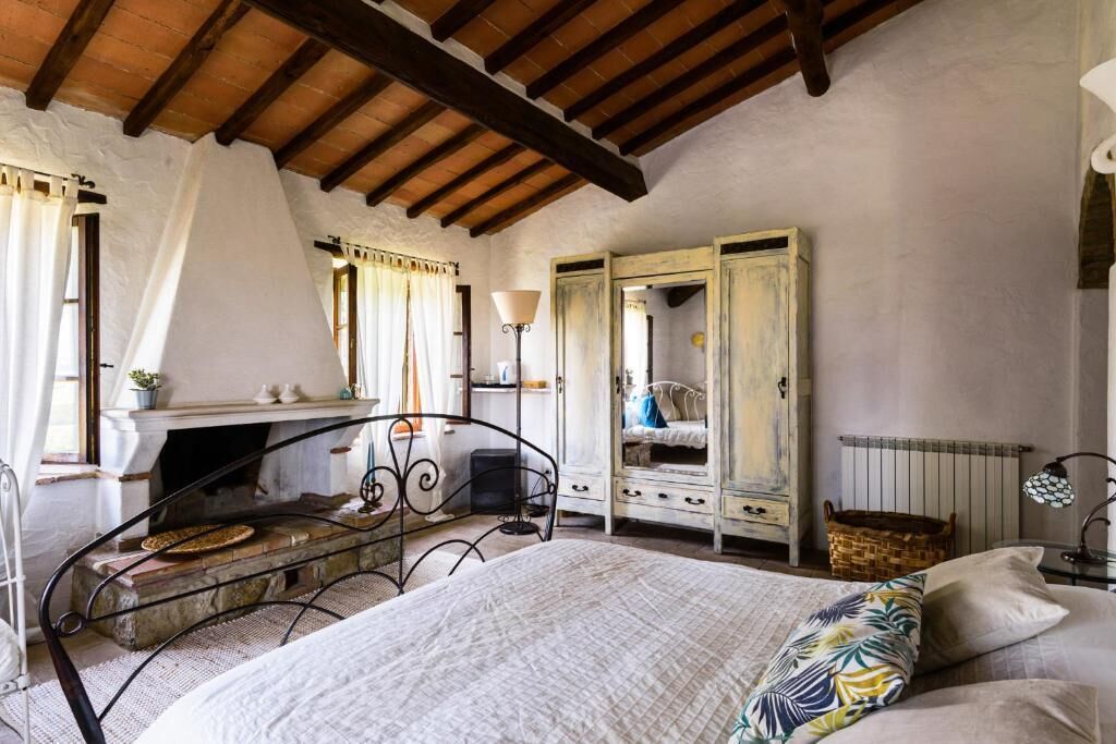 Ein Schlafzimmer mit Bett, Kamin, Kleiderschrank und einem fensterbepflanzten Fenster.