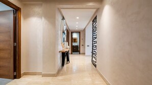 Un couloir avec une porte en bois sur la gauche, un banc et un porte-manteau fixé au mur.
