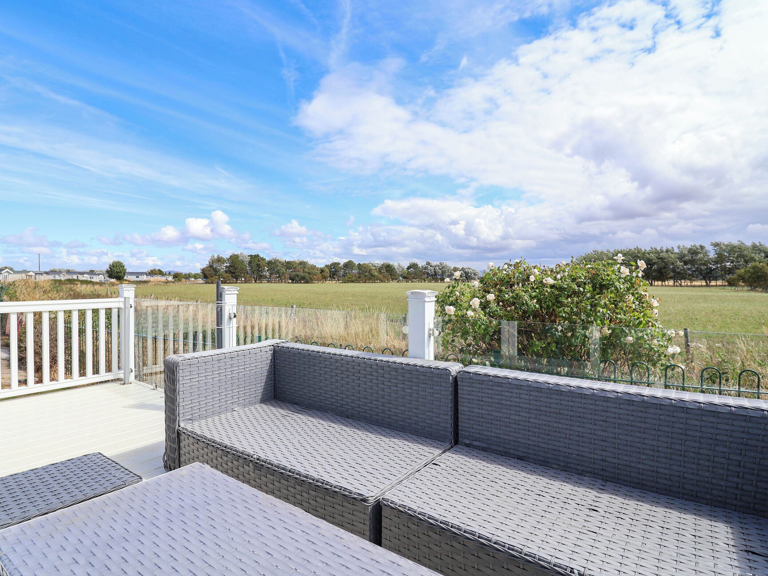 Een overdekt terras met uitzicht op een veld en bomen.