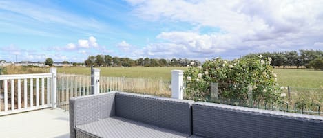 A covered outdoor seating area with a view of a field and trees.