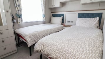 Ein Schlafzimmer mit zwei Betten, einem Kleiderschrank und einem Fenster mit Vorhängen.