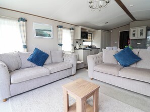 A living room with two sofas, a coffee table, and a kitchen area in the background. - i35 - The Imperial (Abergele)