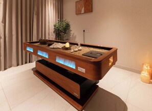 A wooden massage table with a built-in massage head, a candle, and a small plant. - Deluxe Escape  Luxury Wellness Hotel (Jumeirah Village Triangle)
