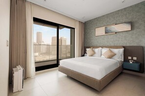 A modern hotel room with a large bed, a view of the cityscape, and a cityscape painting on the wall. - Deluxe Escape  Luxury Wellness Hotel (Jumeirah Village Triangle)