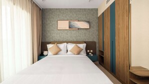 A hotel room with a large bed, a headboard with a painting, a nightstand, and a wardrobe. - Deluxe Escape  Luxury Wellness Hotel (Jumeirah Village Triangle)