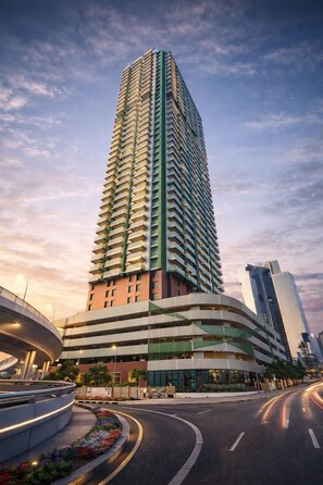 A high-rise building with a curved facade, multiple floors, and a modern design. - Deluxe Escape  Luxury Wellness Hotel (Jumeirah Village Triangle)