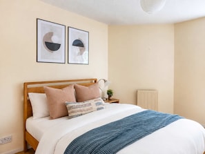 A neatly made bed with a wooden headboard, two pillows, a blue blanket, and a bedside lamp. - Cozy 2BR Near City Centre - Steps to Old Town (Edinburgh)