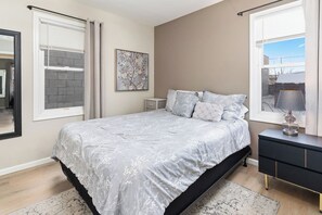 A bedroom with a bed, bedside table, lamp, and artwork on the wall. - Cozy 2 Bedroom Renovated Home (St. Cloud)