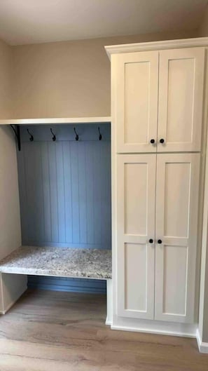 Une pièce dotée d’une banquette intégrée, d’une armoire à deux portes et d’un porte-manteau mural.