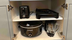 Eine Küche mit einer Kochbox, einem Toaster und einem Mixer auf offenen Regalen.