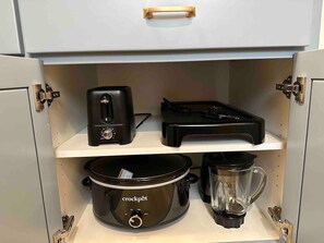 Eine Küche mit einer Kochbox, einem Toaster und einem Mixer auf offenen Regalen.
