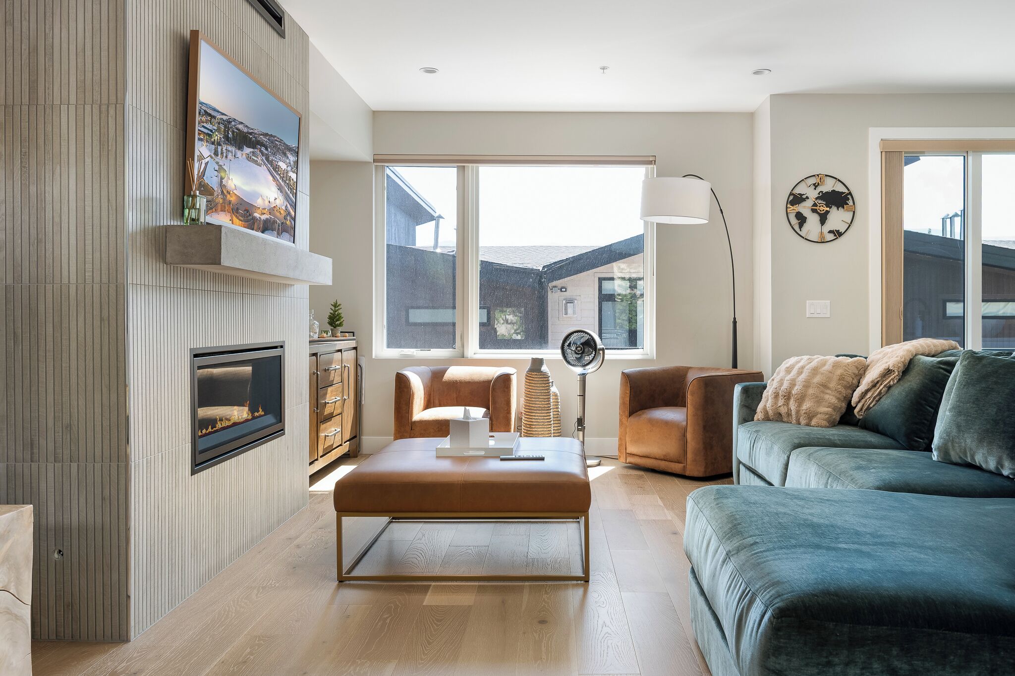 Un salon moderne avec une cheminée, une grande fenêtre et une vue sur l’extérieur.