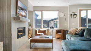 A modern living room with a fireplace, a large window, and a view of the outside. - Luxury Emerald Escape | Hot Tub | Ski Shuttle (Winter Park)