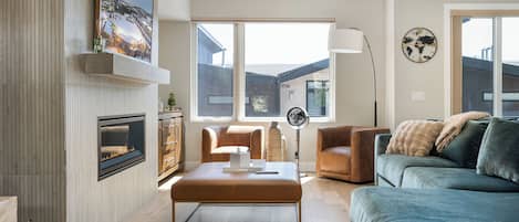 Un salón moderno con chimenea, un ventanal grande y vistas al exterior.