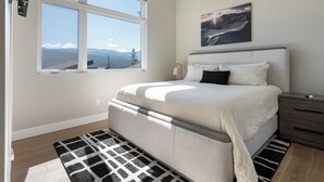 A bedroom with a large window, a bed, a bedside table, and a wall-mounted artwork. - Luxury Emerald Escape | Hot Tub | Ski Shuttle (Winter Park)