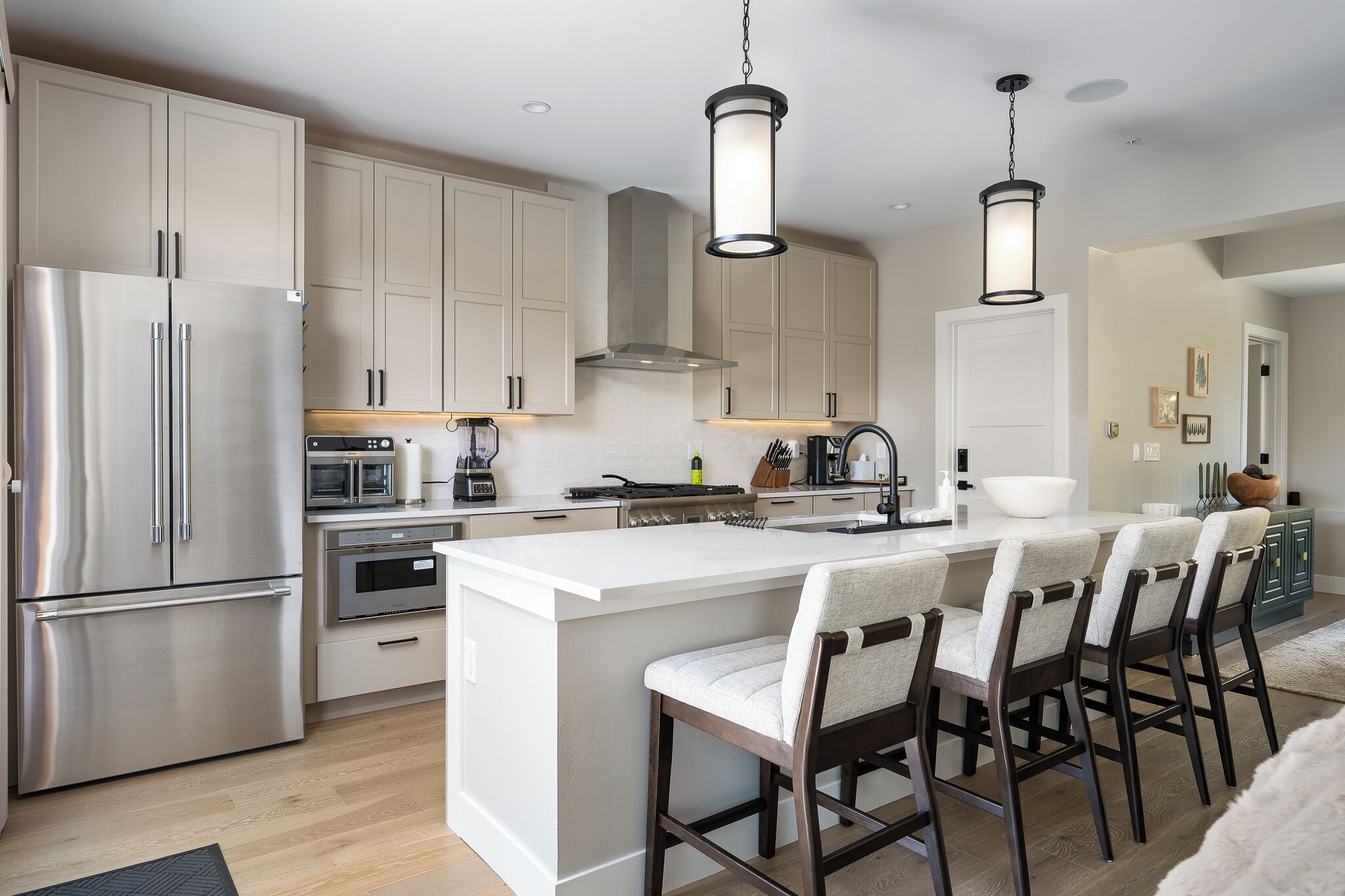 Uma cozinha moderna com eletrodomésticos de aço inoxidável, uma ilha central com banquetas e iluminação pendente.