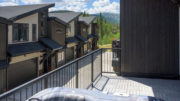 A hot tub on a wooden deck with a view of a row of buildings and mountains in the background. - Luxury Emerald Escape | Hot Tub | Ski Shuttle (Winter Park)