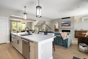 A modern kitchen with a central island, a dining area with a view, and a cozy seating area with a fireplace. - Luxury Emerald Escape | Hot Tub | Ski Shuttle (Winter Park)
