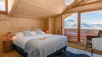 Une chambre à coucher située dans une cabane en bois, avec un lit, une table de chevet, une chaise et une vue sur les montagnes.