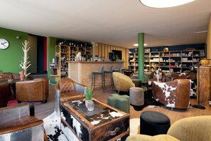 A bar area with stools, a wooden counter, and shelves with bottles.