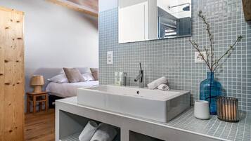 A modern bathroom with a large sink, mirror, and tiled walls.