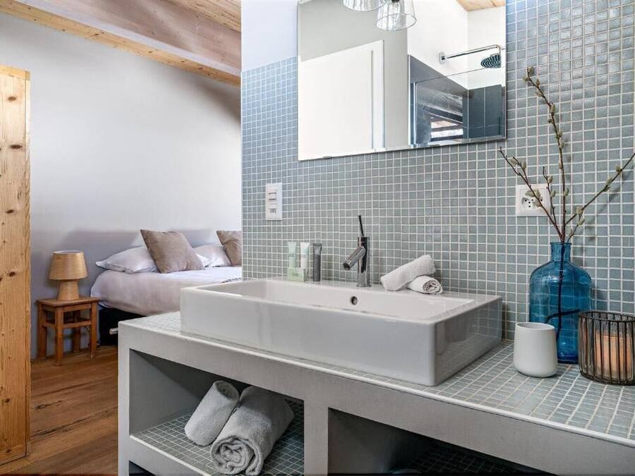 A modern bathroom with a large sink, mirror, and tiled walls.