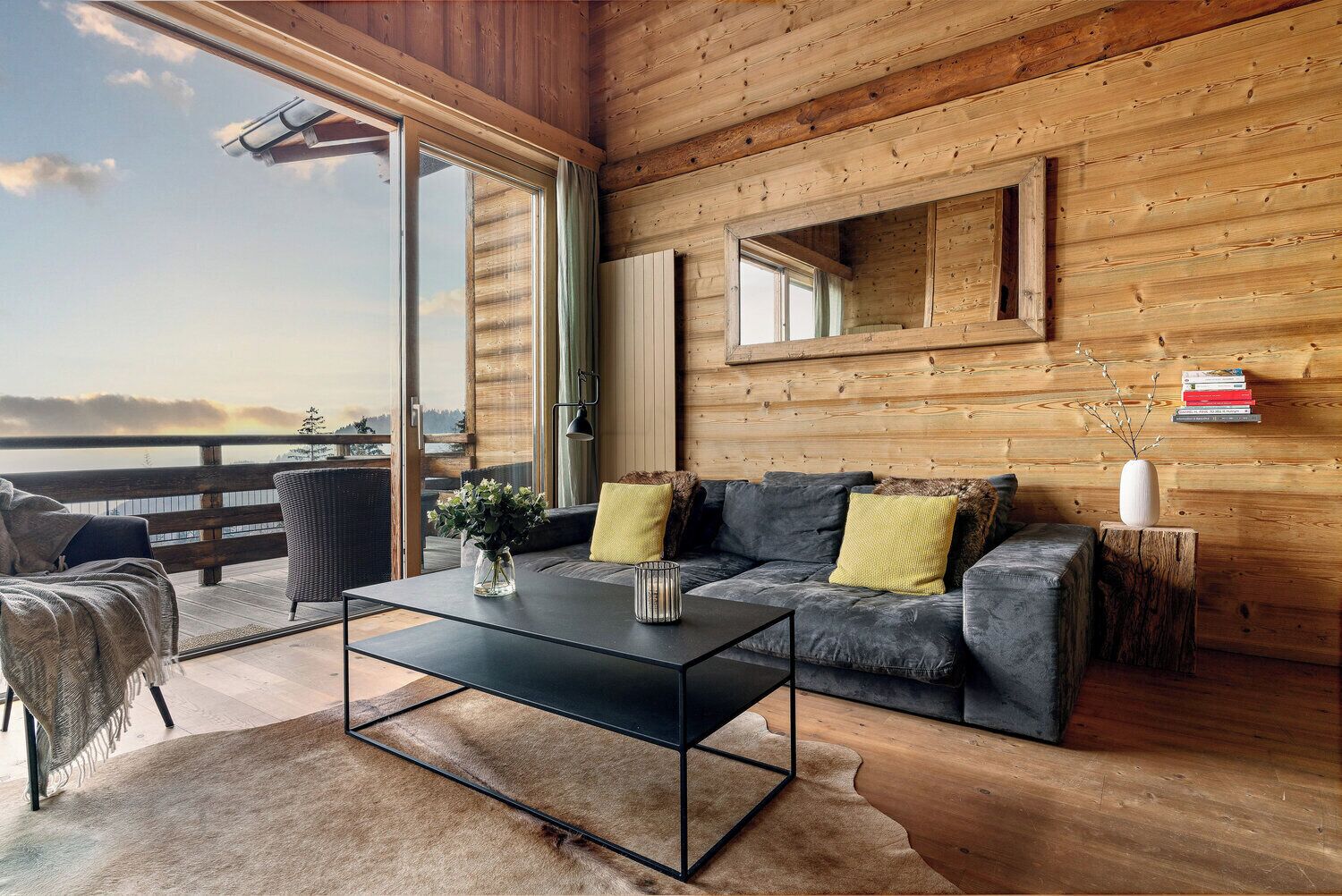 Interior acogedor de una cabaña con un sofá, una mesita de centro y vistas al exterior.