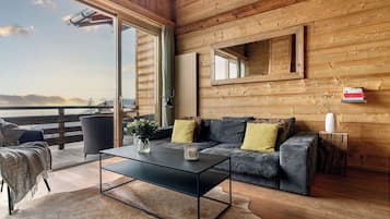 Interior acogedor de una cabaña con un sofá, una mesita de centro y vistas al exterior.