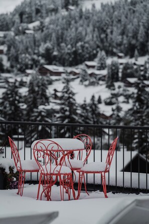 A snow-covered outdoor seating area with red metal chairs and tables.