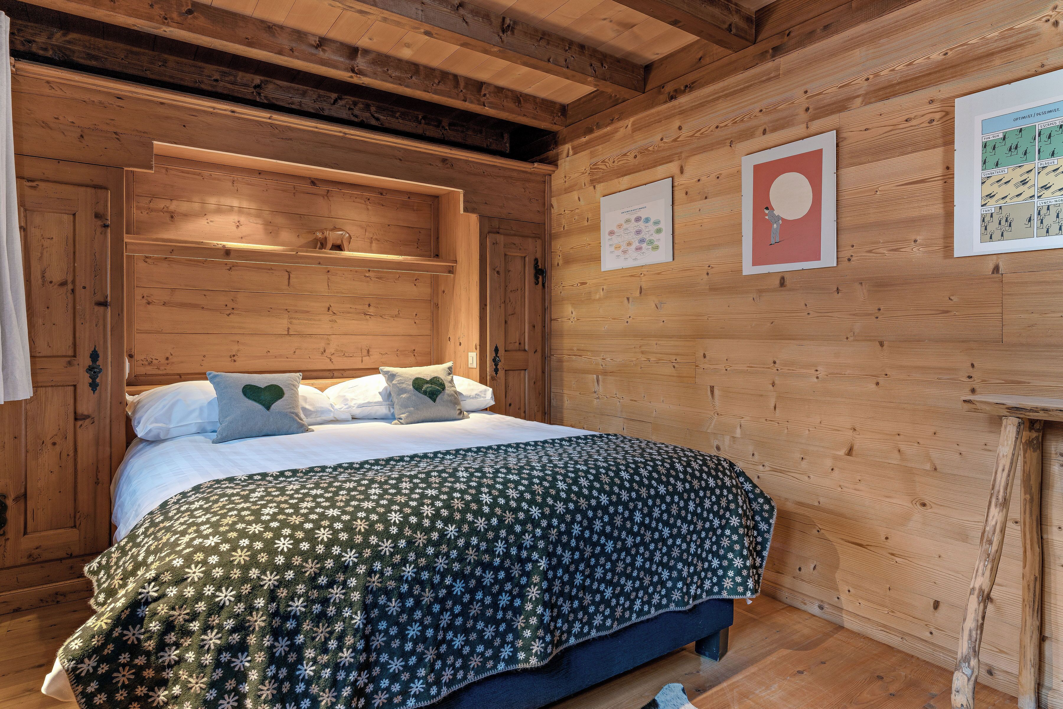 A wooden cabin-style bedroom with a bed, pillows, and a blanket.