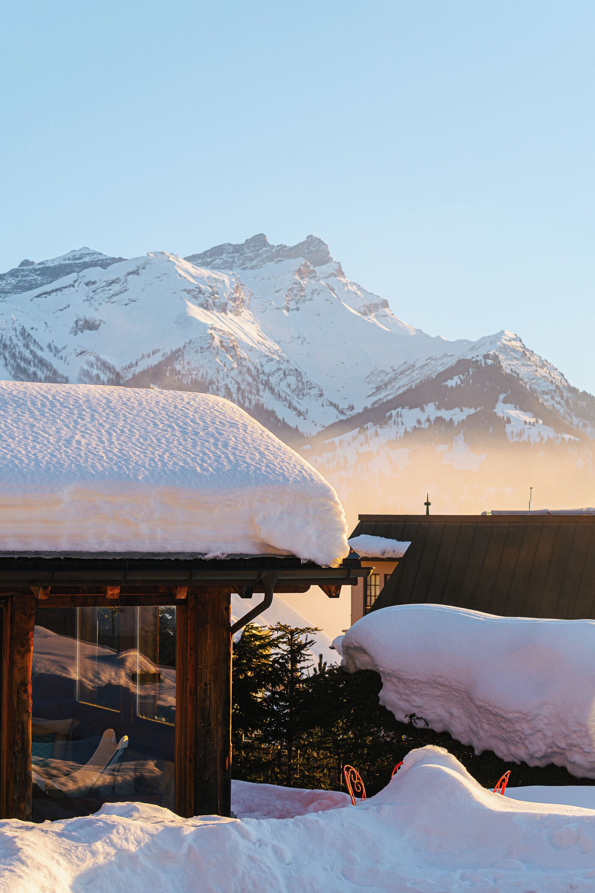 Una montaña cubierta de nieve con una construcción de madera en primer plano.