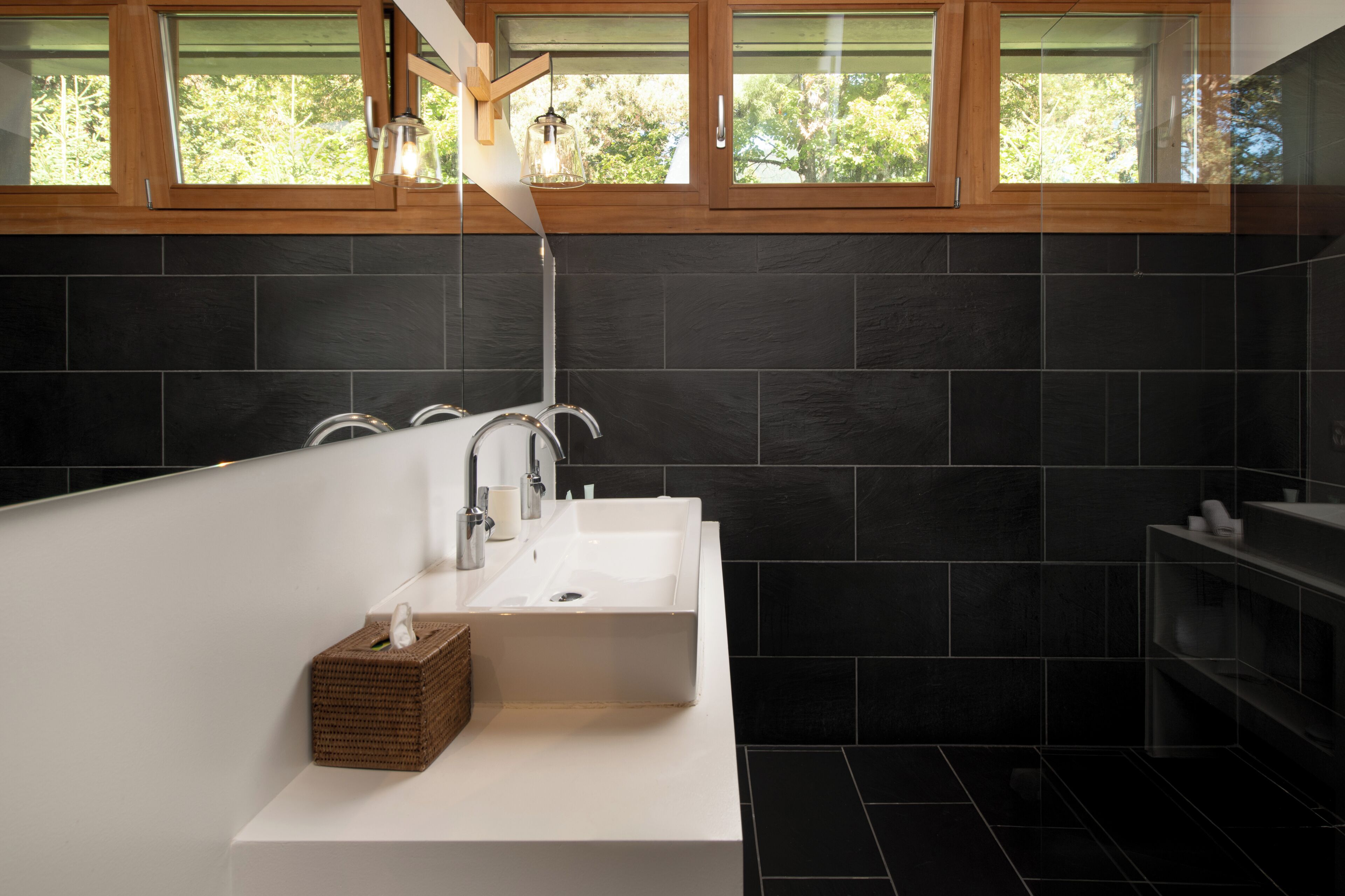 Un baño moderno con una bañera independiente, un lavamanos blanco y un ventanal de madera.