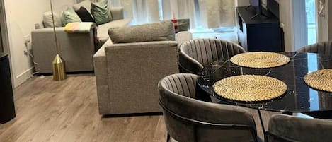 A modern living room with a sofa, a dining table with chairs, and a television.