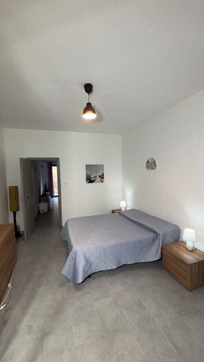 A bedroom with a bed, bedside tables, a painting, and a ceiling light. - A comfortable apartment right in the heart of the city and just a few meters from the sea (Castellammare del Golfo)