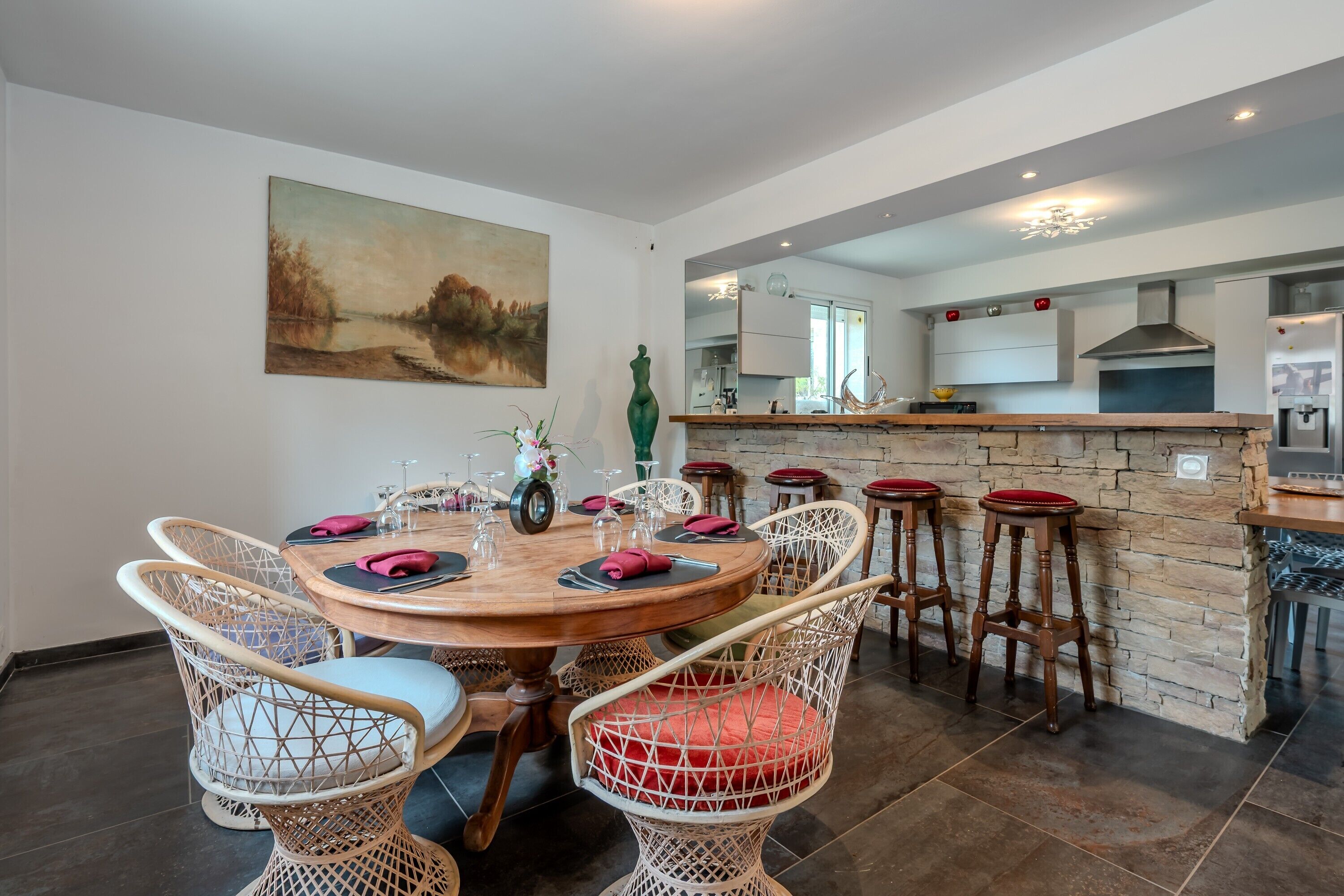 A dining area with a round table, wicker chairs, and a stone accent wall.