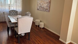 Uma sala de jantar com mesa, cadeiras e um objeto decorativo na parede.