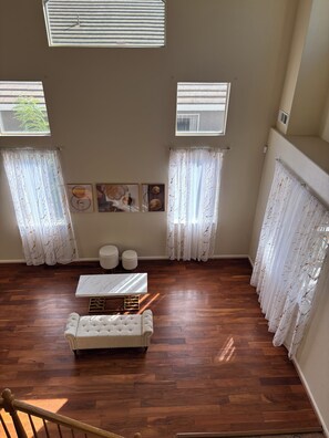 A room with a wooden floor, a white sofa, two small round tables, and a large window with curtains. - 3-bedroom house in enchanting Antioch with cool AC (Antioch)