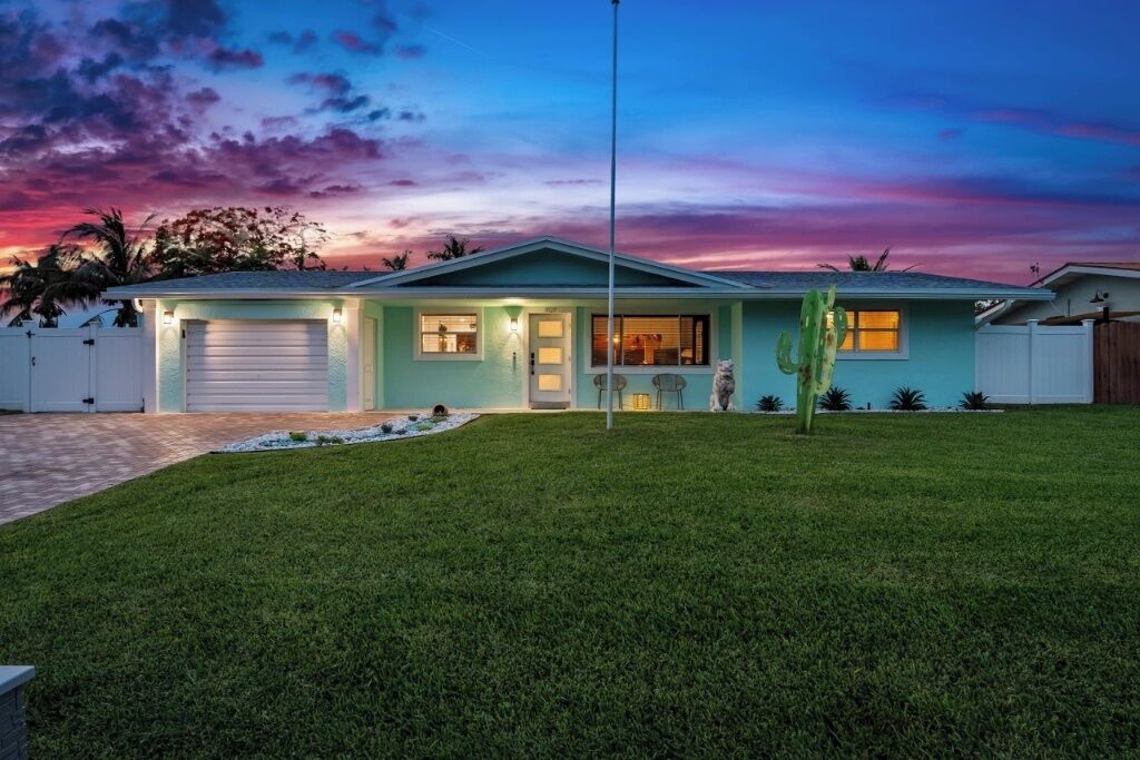 A single-story house with a garage, a well-maintained lawn, and a cactus in the front yard.