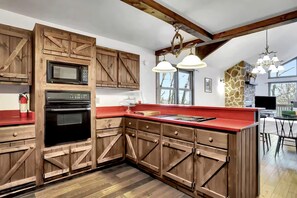A kitchen with wooden cabinets, a red countertop, and a stone accent wall. - Pet Friendly Cabin for Large Groups in the Eastern Panhandle of West Virginia, Surrounded by Scenic Nature and Historic Attractions (Berkeley Springs)