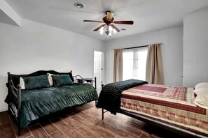 A bedroom with two beds, a ceiling fan, and a window with curtains. - Pet Friendly Cabin for Large Groups in the Eastern Panhandle of West Virginia, Surrounded by Scenic Nature and Historic Attractions (Berkeley Springs)