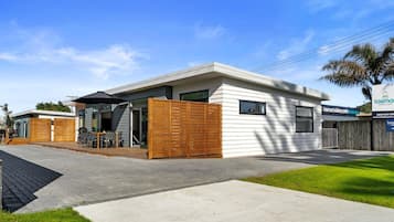 En modern tvåvåningsbyggnad med en täckt uteplats, ett trästaket och en skylt för Tasman Holiday Parks.