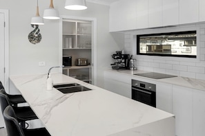 Una cocina moderna con encimera de mármol, electrodomésticos integrados e iluminación colgante.
