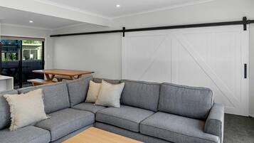 Un salon moderne avec un canapé d’angle, une table basse en bois et une porte coulissante de style rustique.