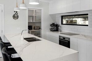 A modern kitchen with a marble countertop, built-in appliances, and pendant lighting.