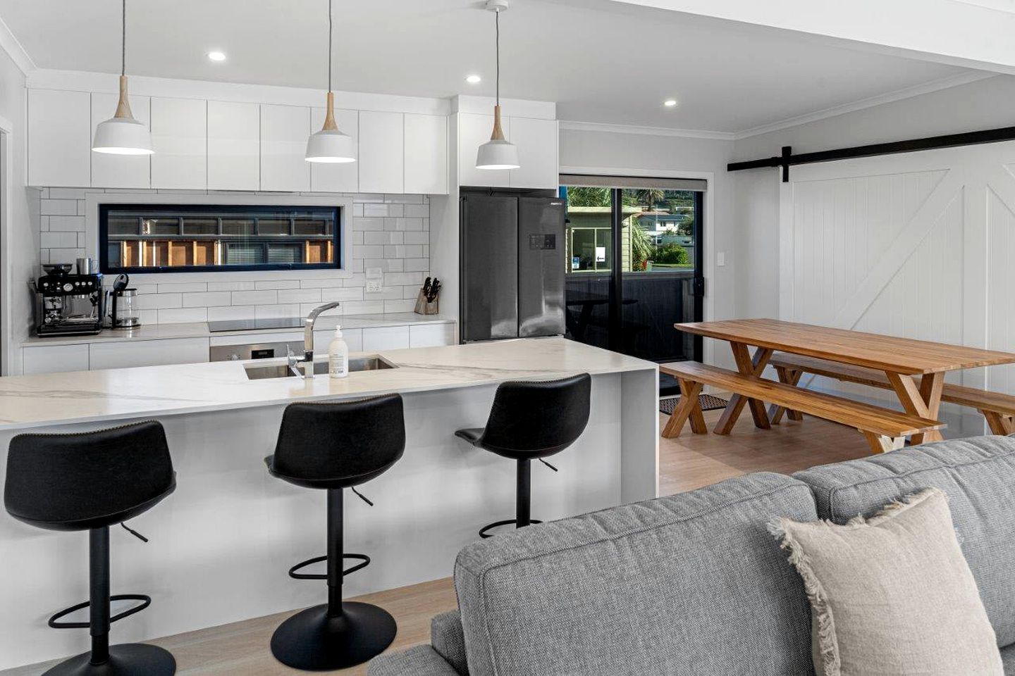 A modern kitchen with a central island, bar stools, and pendant lighting.