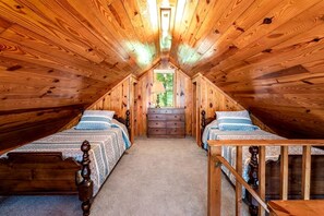 A room with two wooden beds, a dresser, and a window.