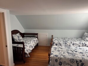 Une chambre avec deux lits en bois, chacun recouvert d’une couvre-lit à motifs floraux et agrémenté d’oreillers assortis.